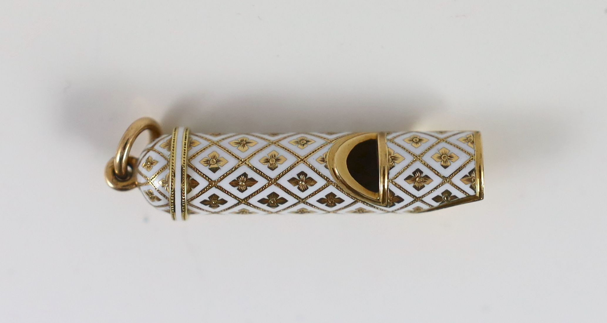 An early 20th century French 18ct gold and white enamel set novelty pendant, modelled as a whistle